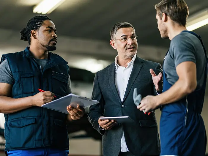 Sydney automotive repair shop owner discussing business expansion plans with mechanics
