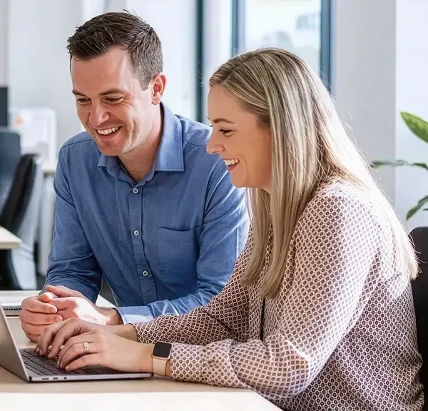 Small business owners reviewing finances on a laptop in a modern office, illustrating the instant asset write‑off extended to 30 June 2026 and potential tax deduction benefits