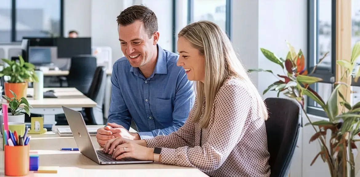 Small business owners reviewing finances on a laptop in a modern office, illustrating the instant asset write‑off extended to 30 June 2026 and potential tax deduction benefits