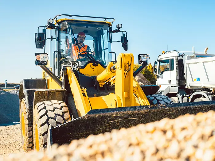 A front-end loader grading material at a construction site for an infrastructure and commercial development business